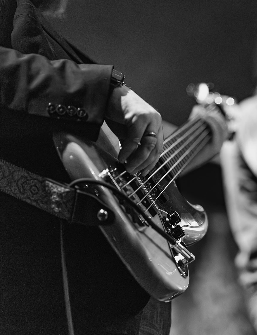 Bassist's hands at the bridge, leather paisley strap